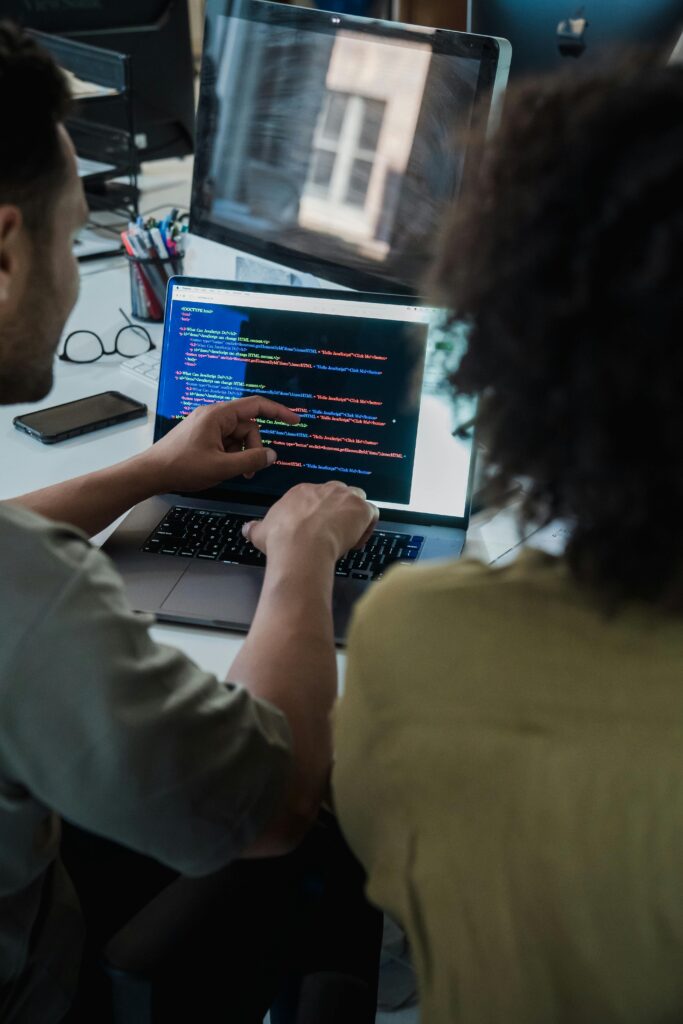 pexels-photo-12899151-12899151 Two adults collaborating on programming tasks using a laptop in an office setting.
